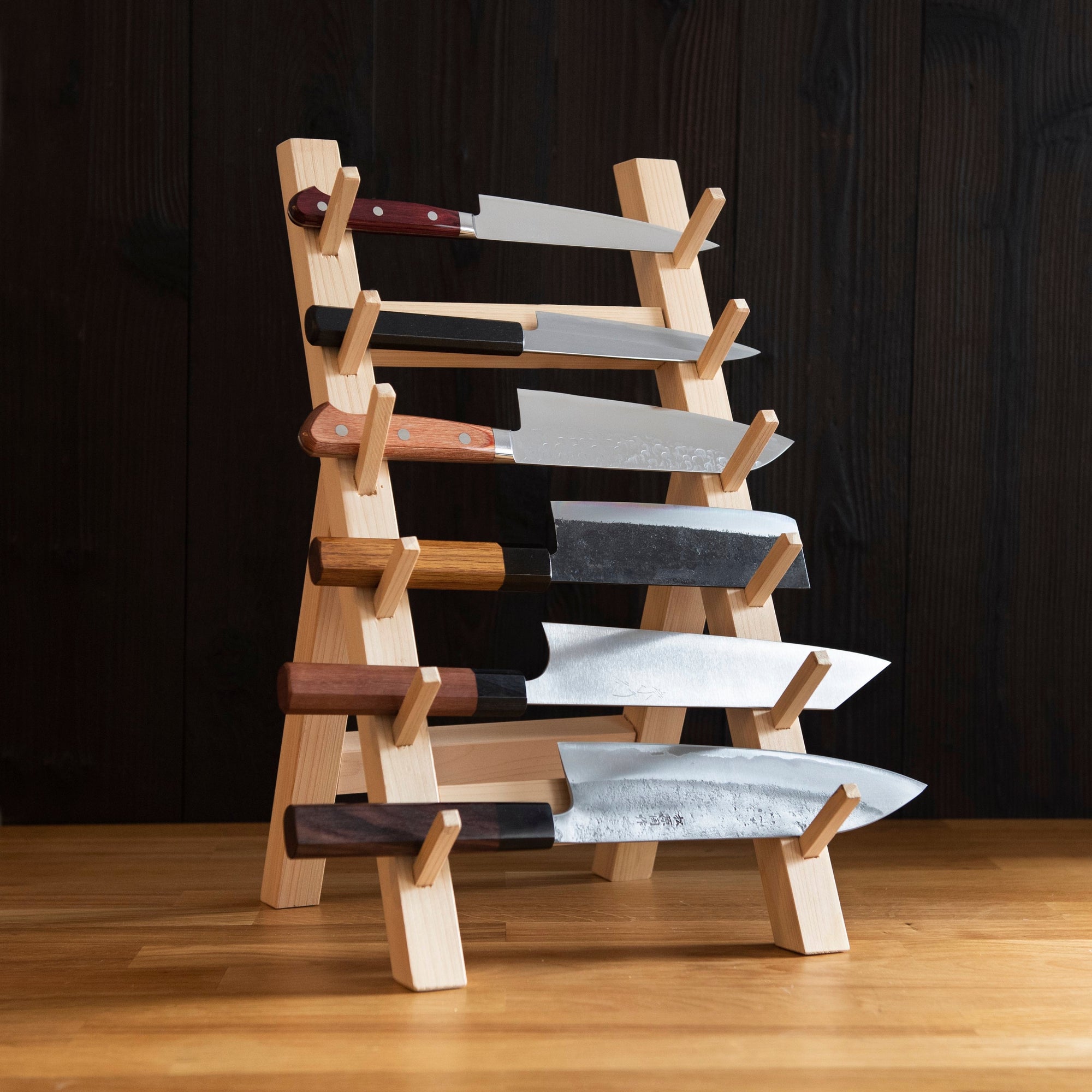 a collection of 6 Japanese kitchen knives displayed on a wooden rack