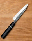 Paring knife with a black handle on a wooden surface