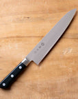 Chef's knife with a black handle on a wooden cutting board