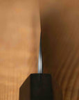 close up of knife blade against a wooden background