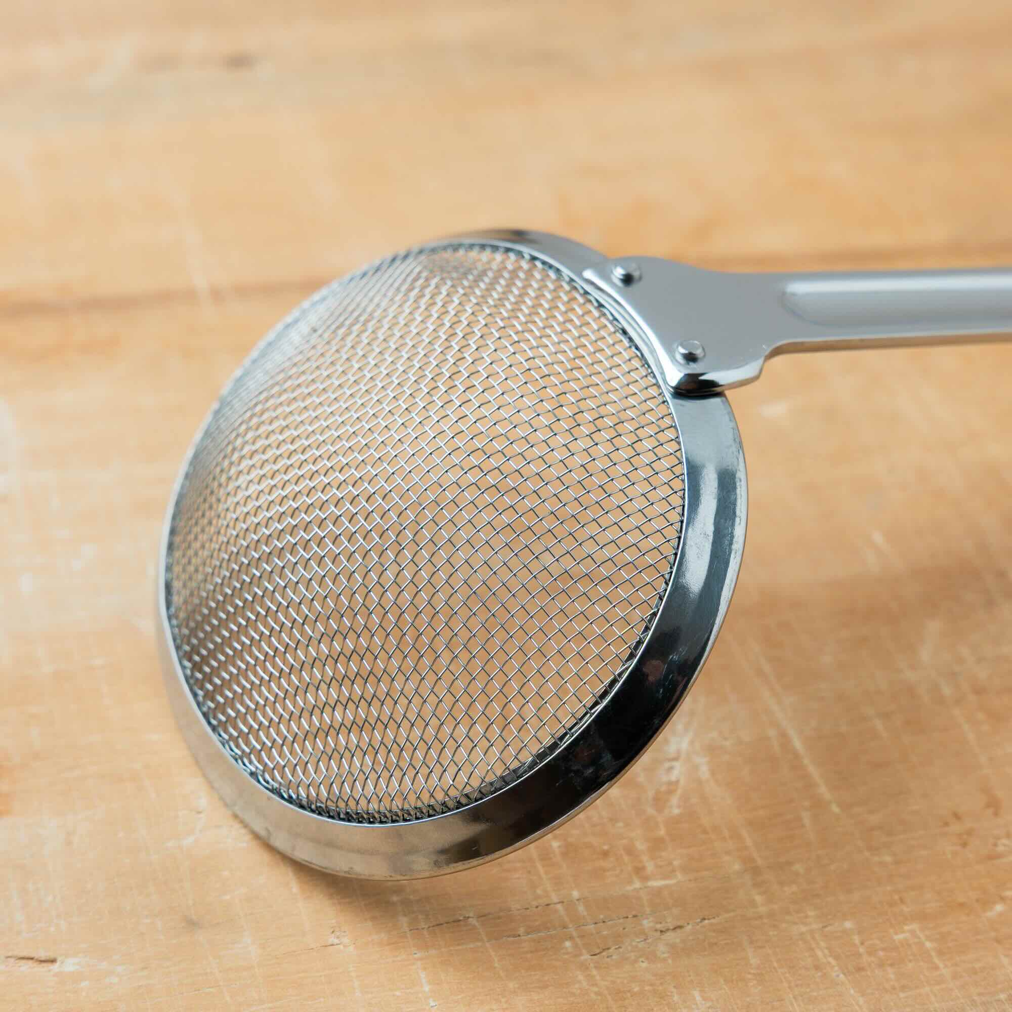 Metal strainer on a wooden surface