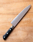 Chef's knife with a black handle on a wooden cutting board